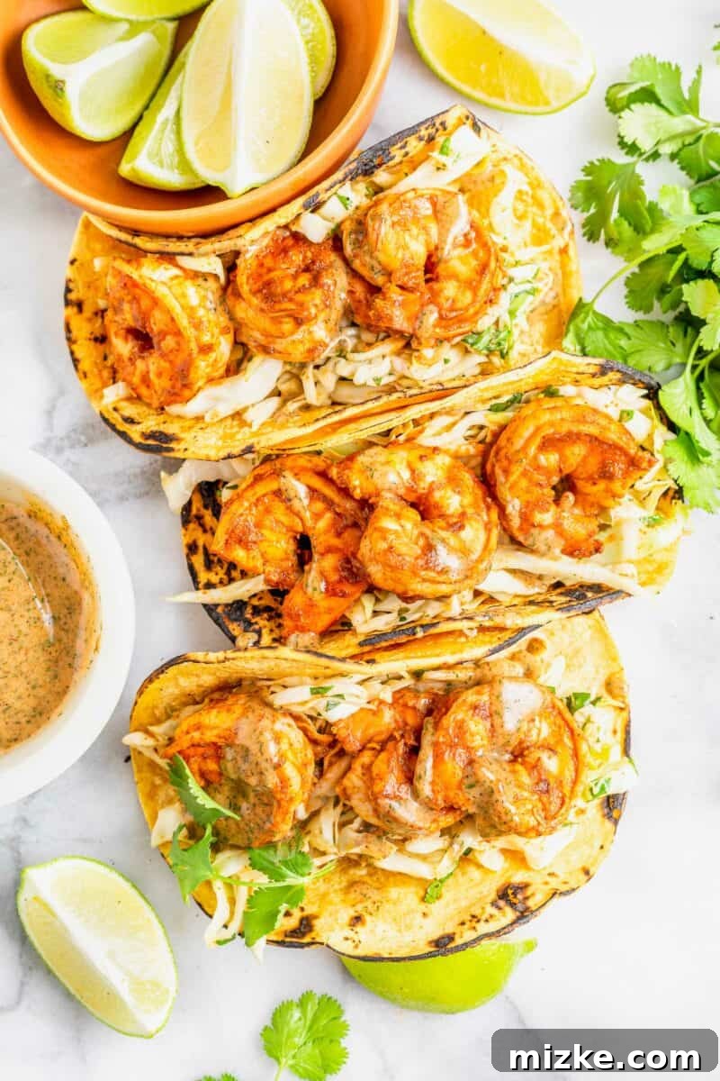 Smoky Chipotle Shrimp Tacos 2 Three perfectly assembled chipotle shrimp tacos, vibrant and ready to eat, are placed on a clean white surface.
