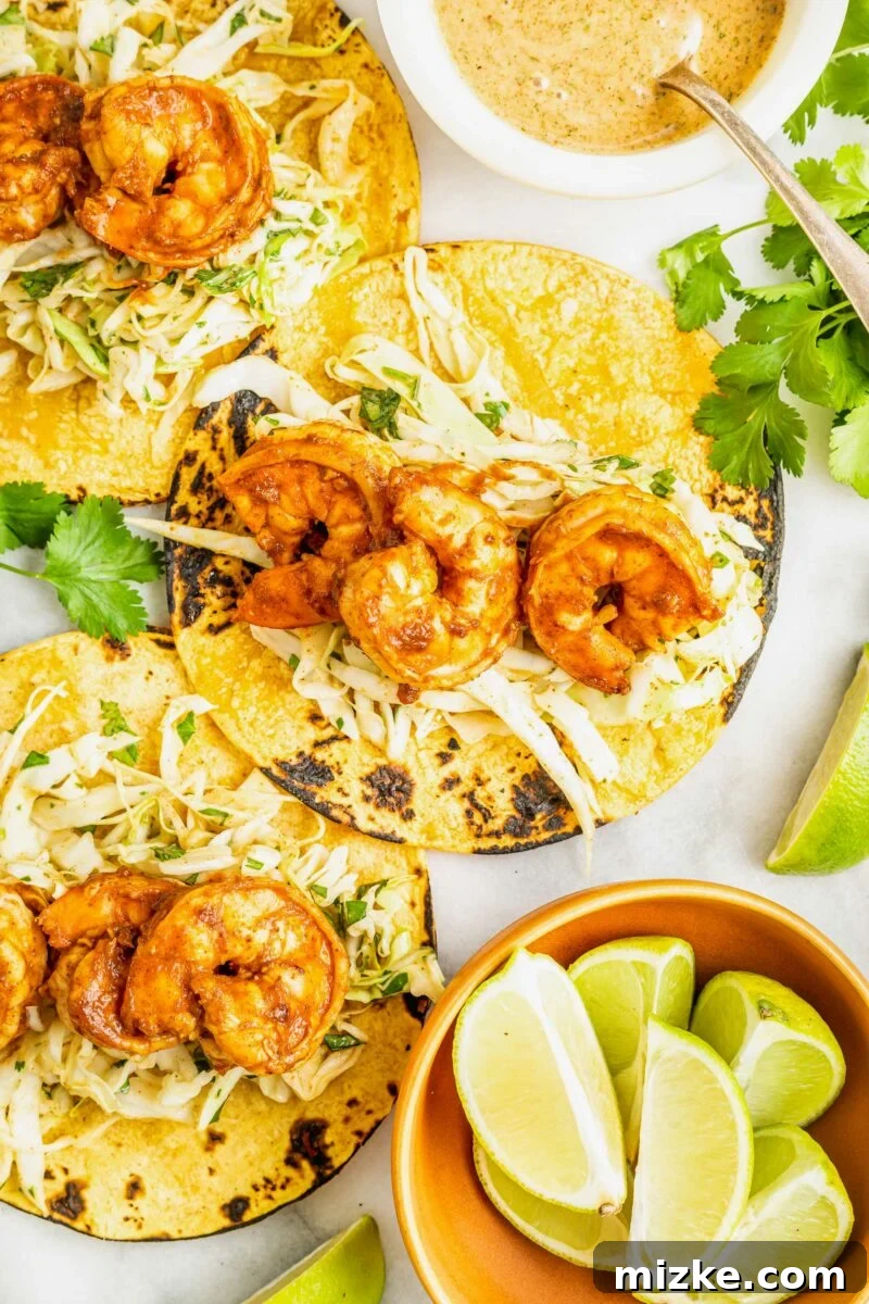 Smoky Chipotle Shrimp Tacos 3 Delicious chipotle ranch sauce and fresh lime wedges are perfectly placed next to a serving of three shrimp tacos, highlighting the vibrant garnishes and rich flavors.