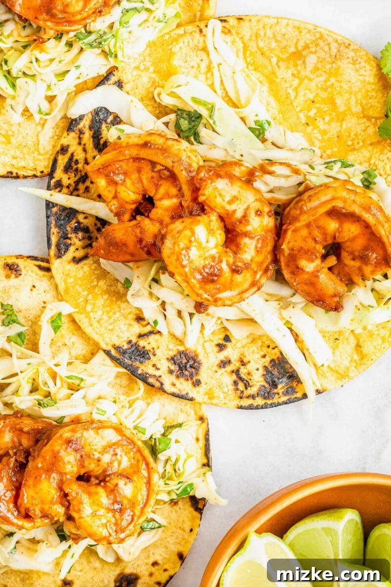 Smoky Chipotle Shrimp Tacos 4 A single perfectly cooked chipotle shrimp is delicately placed on a fresh corn tortilla, ready to be adorned with slaw and sauce.