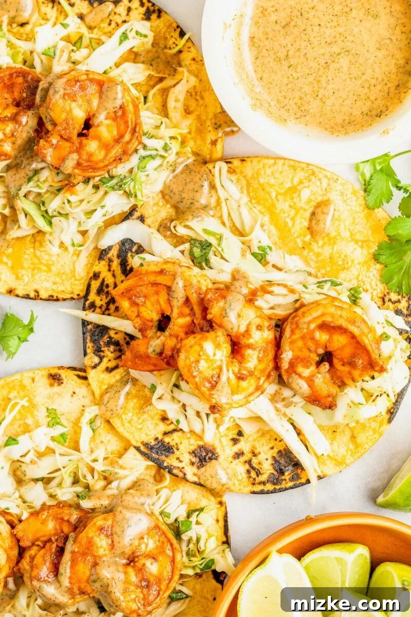 Smoky Chipotle Shrimp Tacos 5 Three perfectly filled corn tortillas, brimming with the vibrant cilantro-lime slaw and succulent chipotle shrimp, are presented on a rustic board.