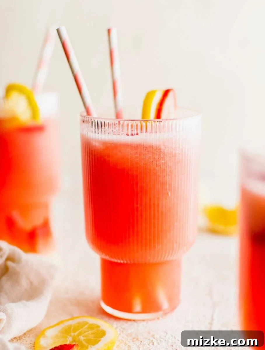 Zesty Summer Sips 3 Two straws and fruity garnishes, including lemon slices and strawberry halves, are elegantly placed in and on a glass of vibrant summer lemonade.