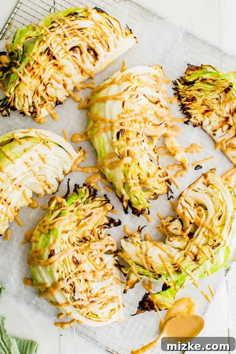 Several slices of cabbage have been grilled and are drizzled with a light orange sauce. 