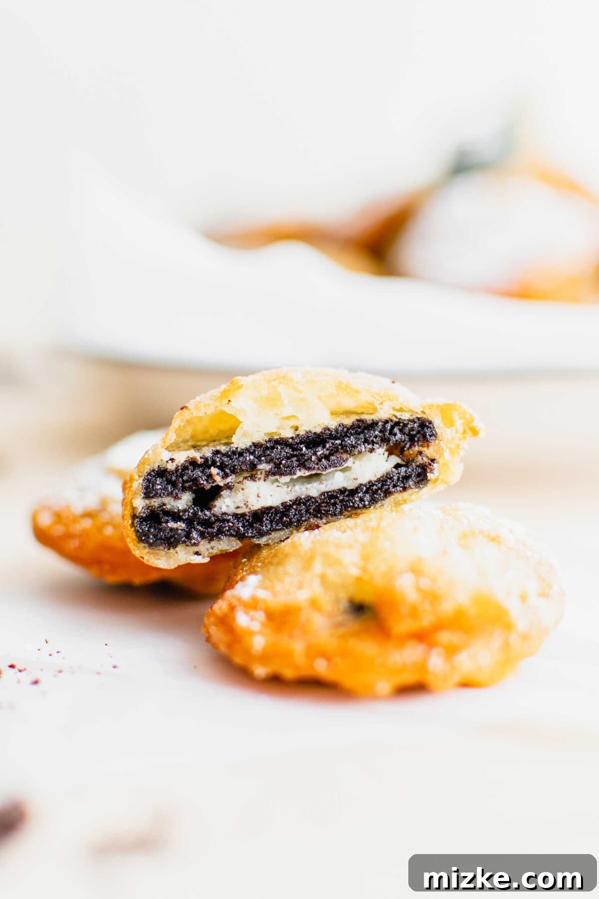 Oreo Fritters 3 A single deep fried Oreo, sliced in half to perfectly display the melted cookie and cream filling inside the golden batter.
