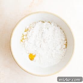 Pancake batter and egg being mixed in a large bowl, ready for dipping Oreos.