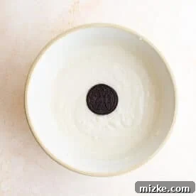 An Oreo being carefully dipped into a bowl of thick pancake batter.