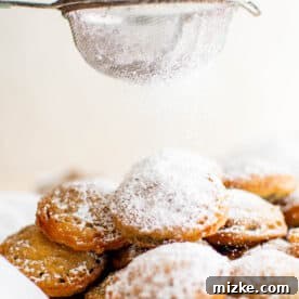 Freshly deep fried Oreos being dusted with powdered sugar, creating an appetizing white coating.