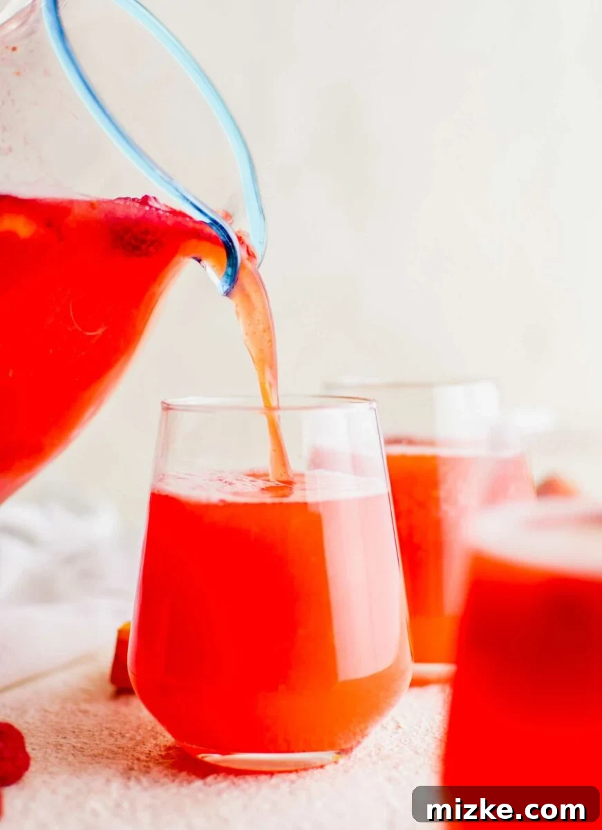 Cool Summer Delight 3 Refreshing summer punch is being carefully poured from a clear pitcher into an elegant small wine glass, showcasing its rich color and floating fruit.