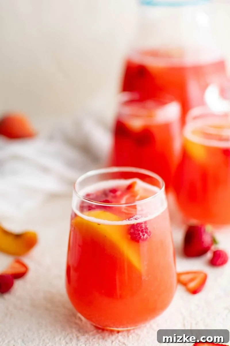 Cool Summer Delight 4 A glass of colorful summer punch, garnished with slices of fresh fruit, shows the blend of ingredients within.