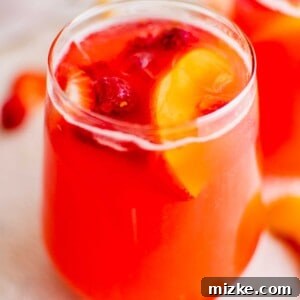A vibrant pitcher of refreshing summer punch, garnished with fresh fruit, stands ready to be served.