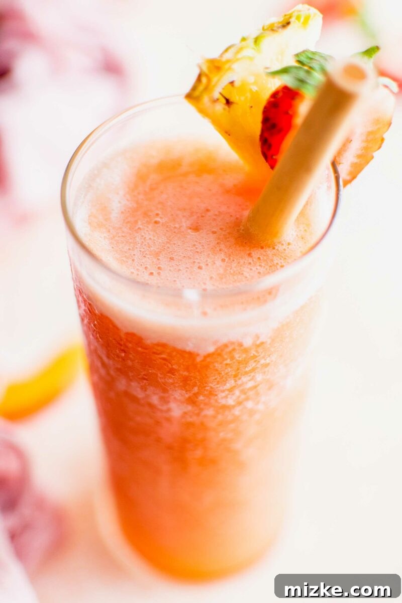 Summer's Spirited Slush 3 A tall glass filled with a bright orange slushy, garnished with fresh berries and a slice of citrus, ready to be enjoyed on a sunny day.