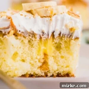 A square slice of cake is revealed with banana pudding inside and topped with whipped topping and banana slices.