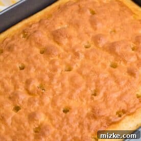 Ultimate Banana Pudding Poke Cake 5 Holes are poked across the top of a baked white cake.