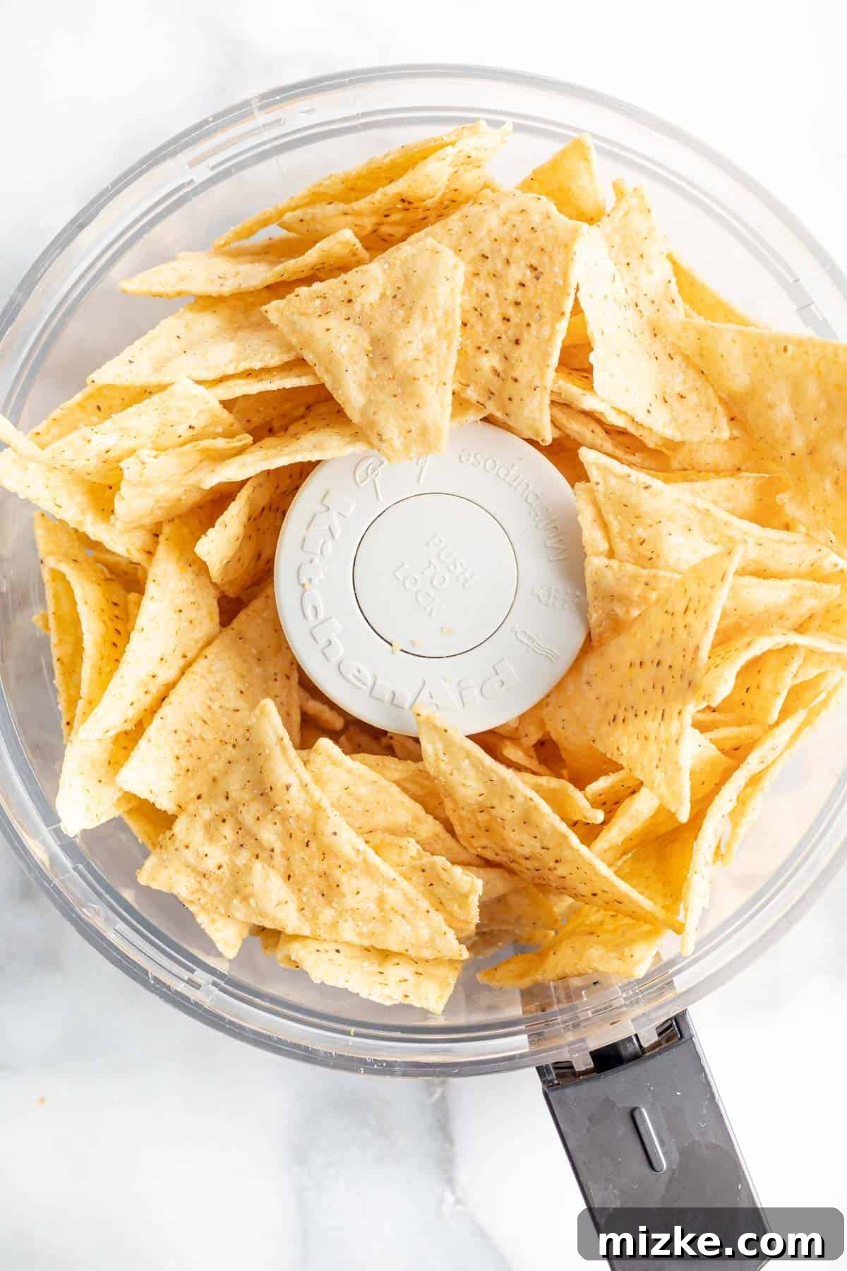 Southwestern Tilapia Crunch 3 Tortilla chips are placed in the bowl of a food processor, ready to be crushed for the tilapia crust.