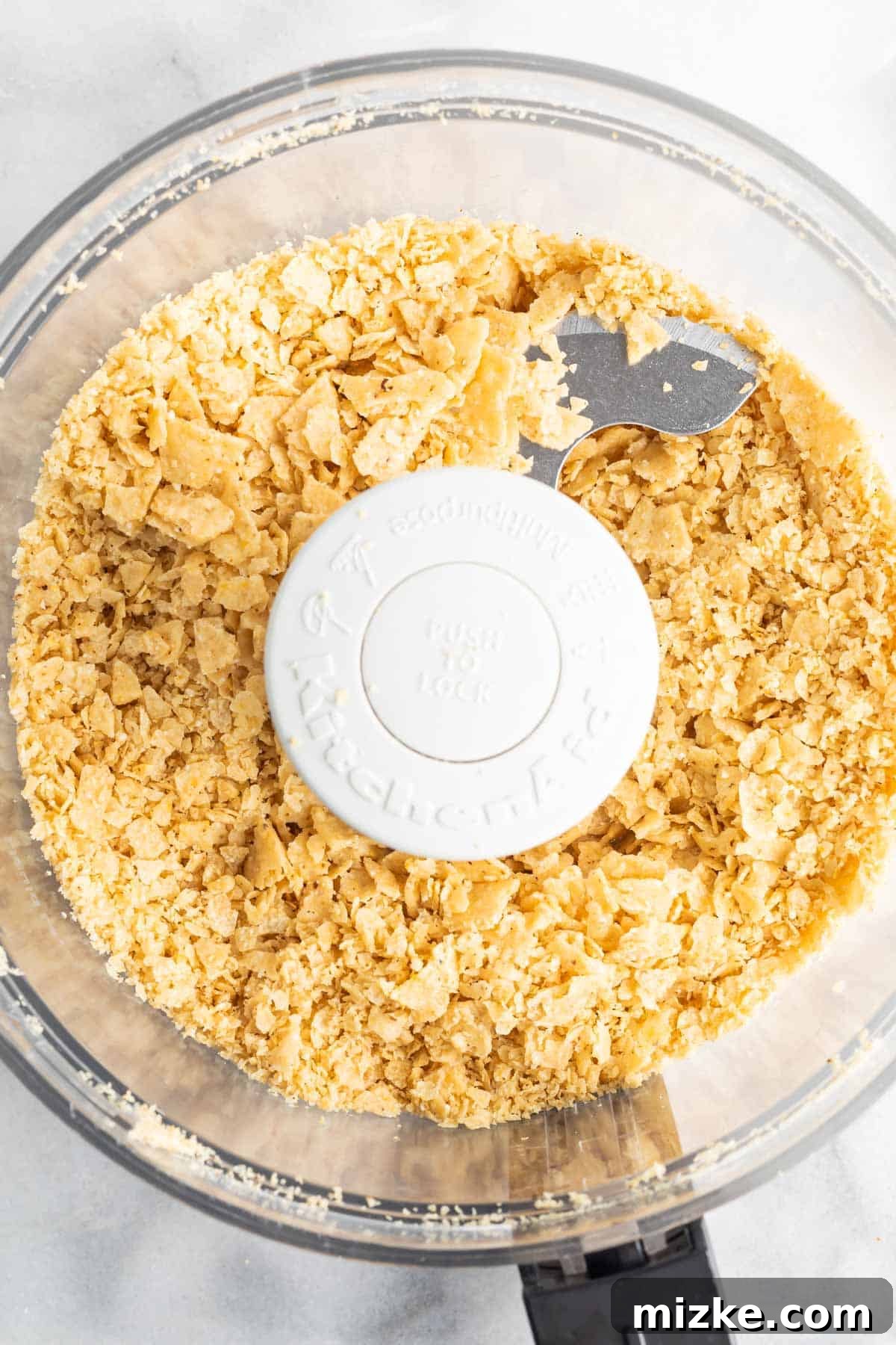 Southwestern Tilapia Crunch 4 Finely crushed tortilla chips with some larger pieces for texture in the bowl of a food processor.