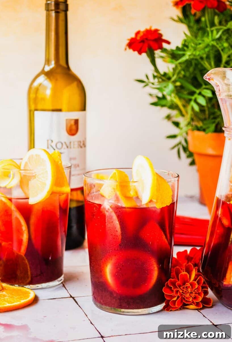 Several glasses are filled with vibrant red sangria and slices of citrus. 