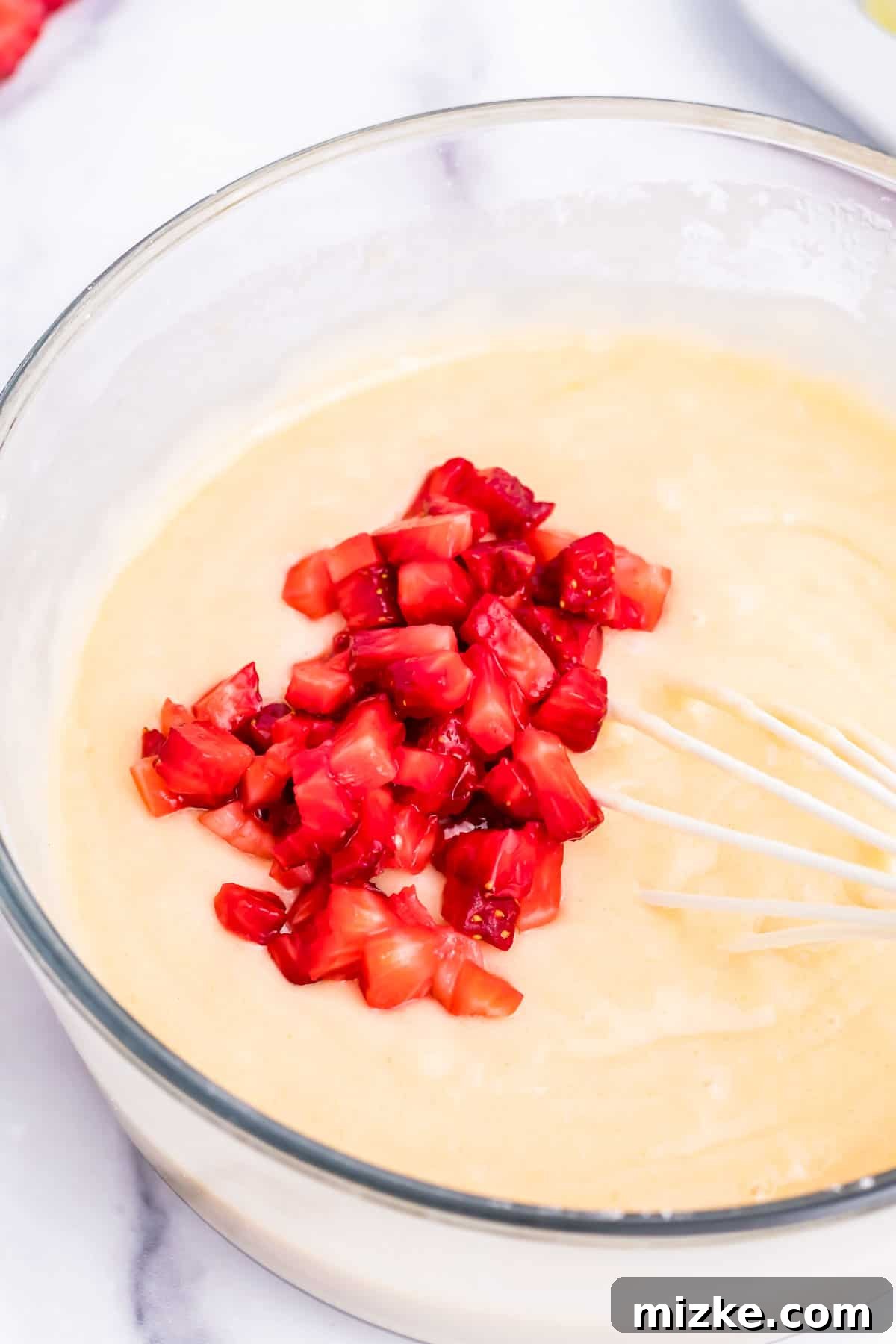Strawberry Oven Donuts 4 Freshly chopped strawberries being gently folded into the donut batter in a mixing bowl.