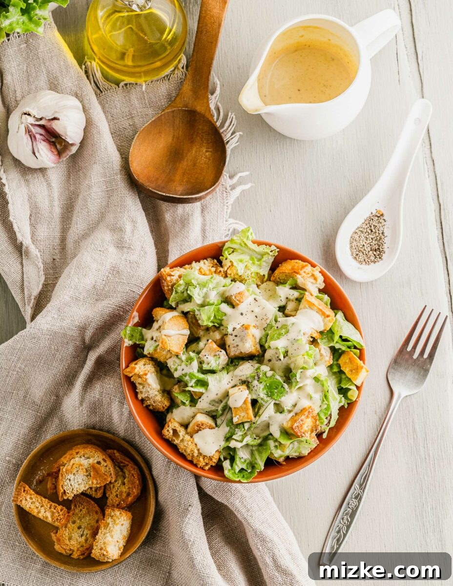 Plant-Based Caesar Salad 4 A fork is placed next to a bowl filled with Caesar salad, ready to be enjoyed.