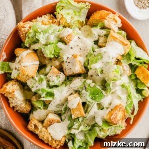 Close-up of a vibrant vegan Caesar salad with croutons and tofu.