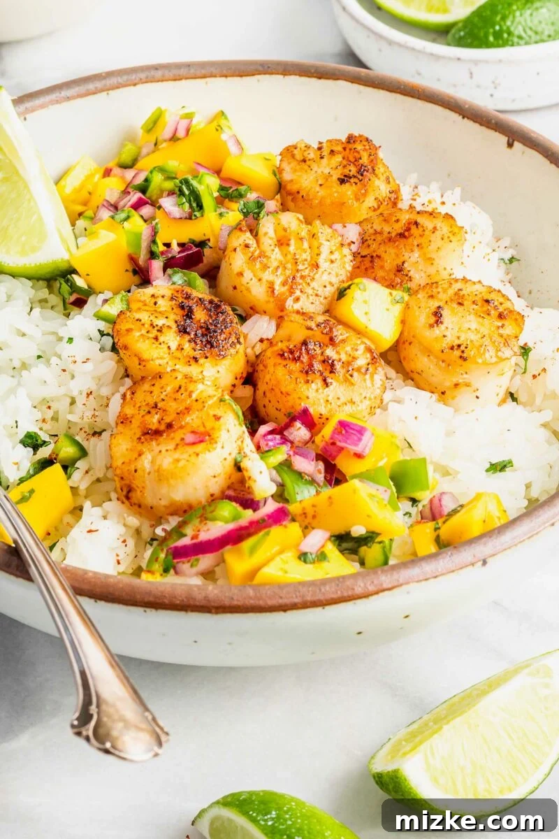 Seared Cajun Brown Butter Scallops 3 A beige and white bowl artfully arranged with a base of rice, vibrant relish, and perfectly seared Cajun Brown Butter Scallops.
