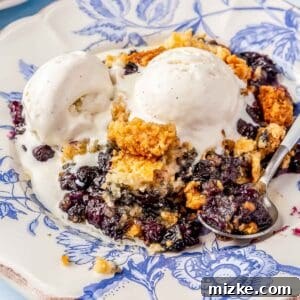 A delectable image of blueberry dump cake with melted vanilla ice cream on a blue china plate, ready to be served. This captures the deliciousness of the dessert.