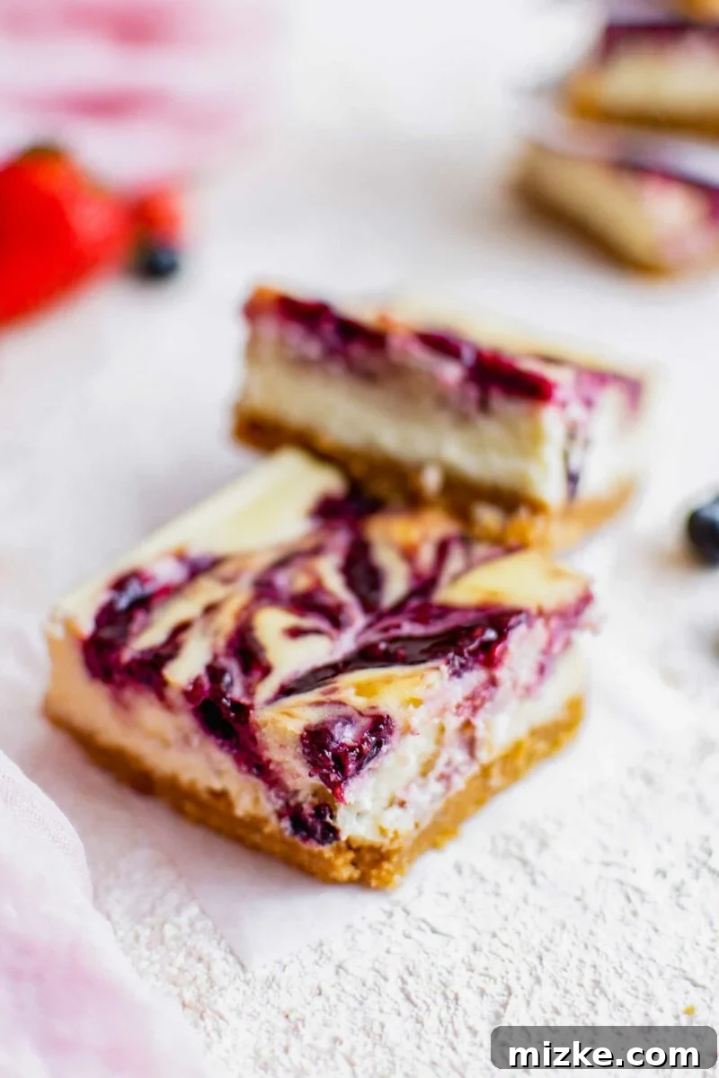 Vibrant Berry Cheesecake Squares 4 A single Triple Berry Cheesecake Bar with a distinct berry swirl, presented on a small piece of parchment paper, highlighting its intricate design.