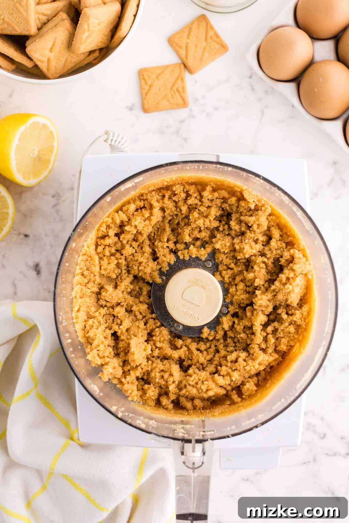 Bright Lemon Tart 5 The lemon tart crust mixture, a harmonious blend of crushed shortbread cookies and melted butter, is perfectly combined in the bowl of a food processor, appearing moist and ready to be pressed into the tart pan.