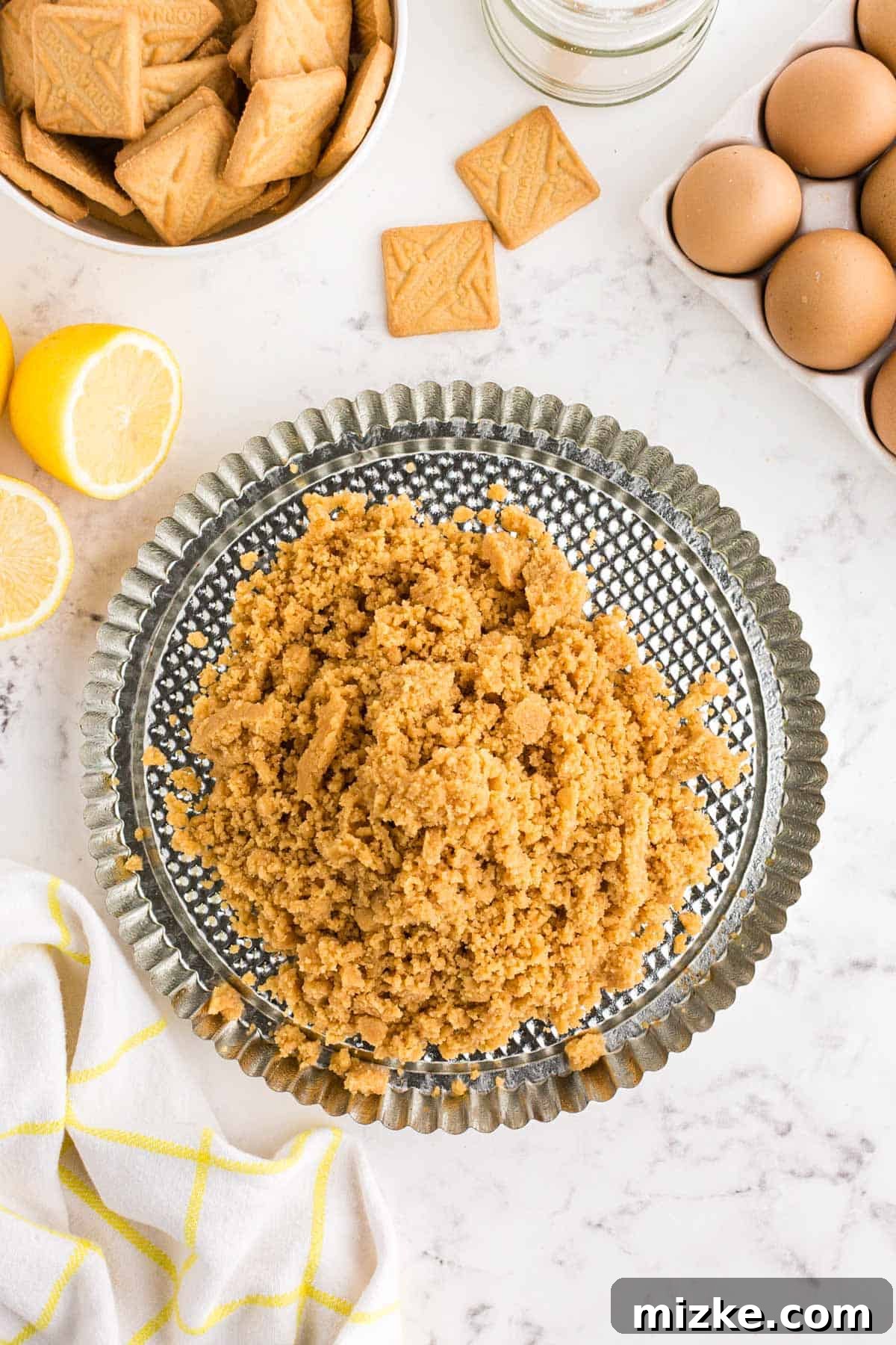 Bright Lemon Tart 6 Finely crushed shortbread cookie crumbs, thoroughly moistened with butter, are spread evenly across the bottom of a metal tart pan, ready to be firmly pressed into a cohesive crust.