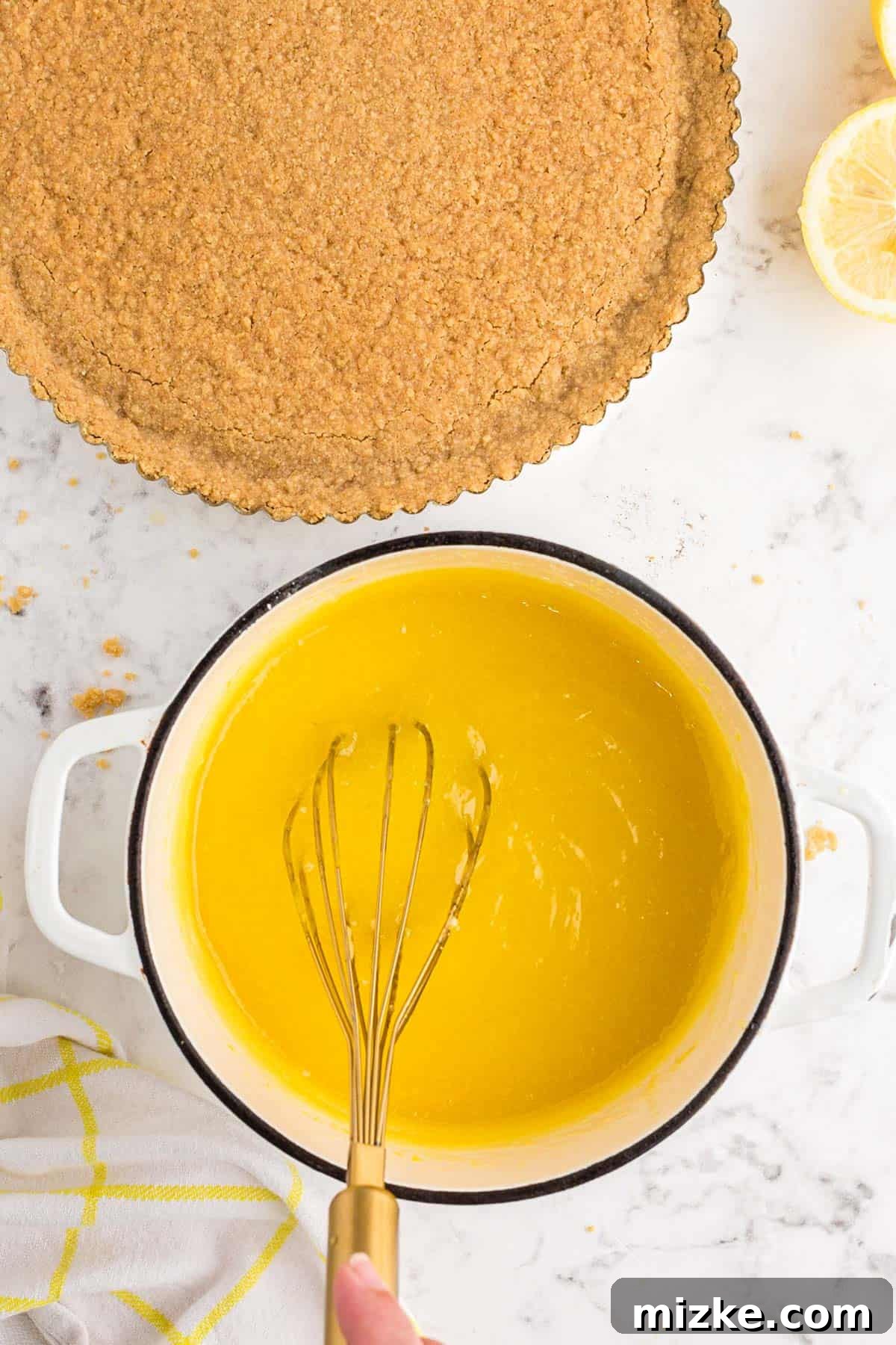 Bright Lemon Tart 8 A whisk vigorously mixing a creamy, pale yellow lemon curd mixture in a small saucepan on a stovetop, illustrating the crucial cooking process to achieve the desired thickness and smooth consistency.
