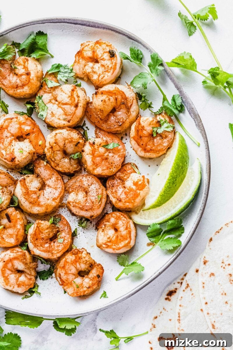 A plate of grilled shrimp is garnished with fresh cilantro and lime wedges, ready to be served.