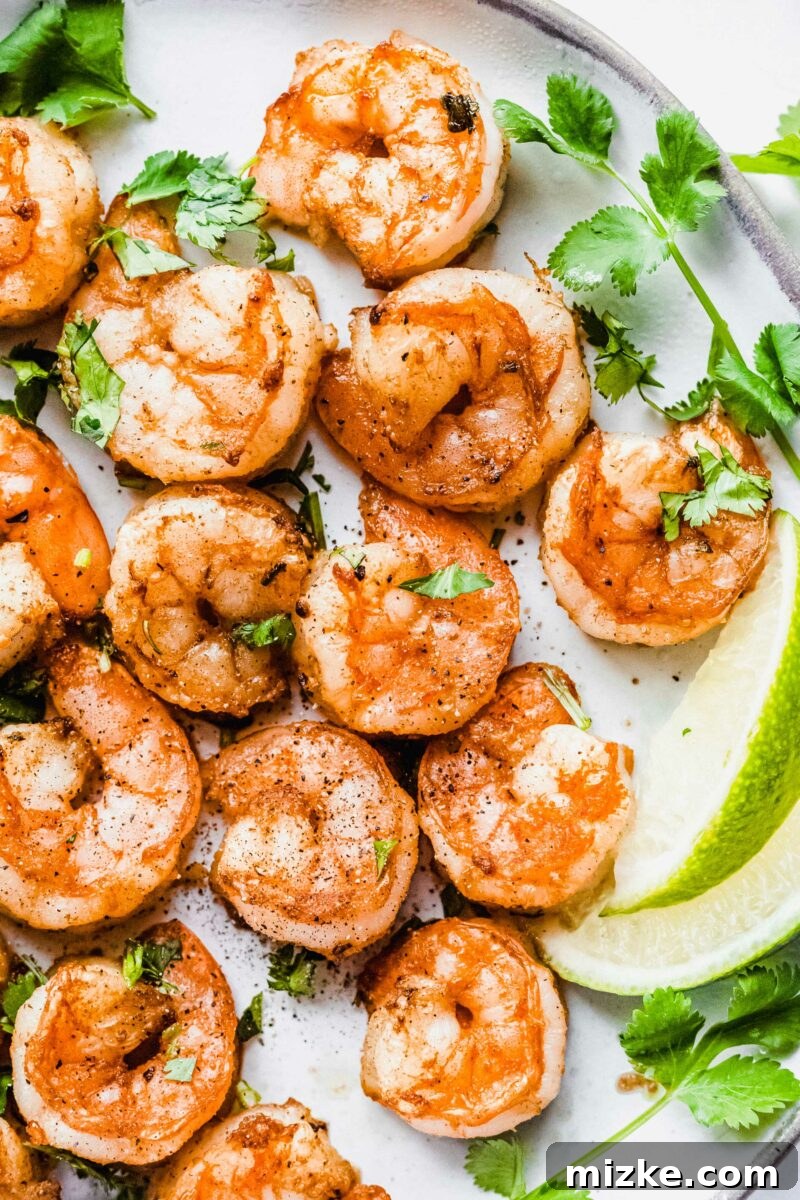 A serving of perfectly cooked shrimp, seasoned and ready for tacos, presented on a white plate.