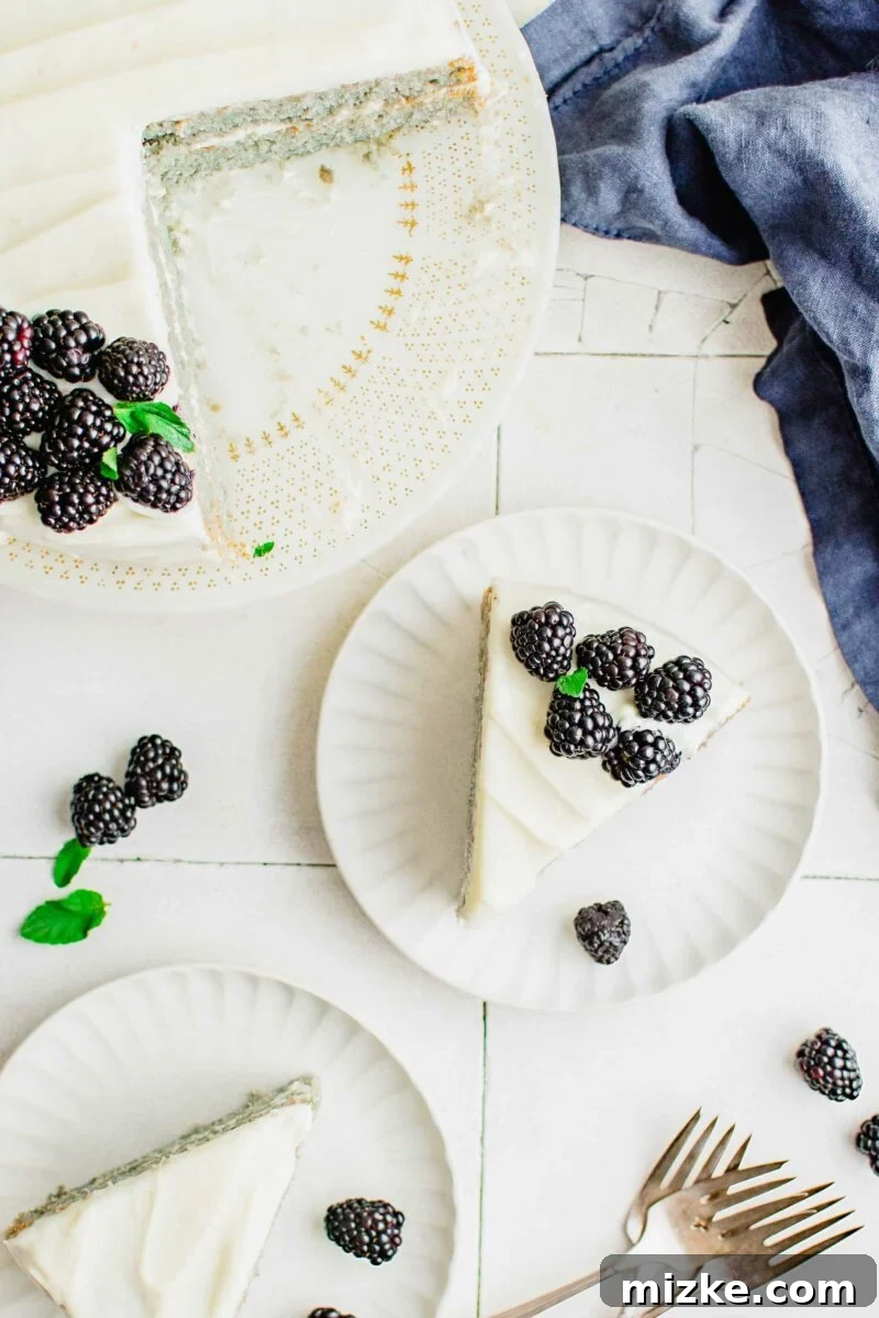 A delectable slice of blackberry cake on a white plate, elegantly garnished with fresh blackberries and mint for a beautiful presentation.