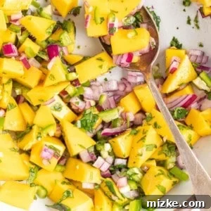 Mixed mango relish in a bowl with a spoon