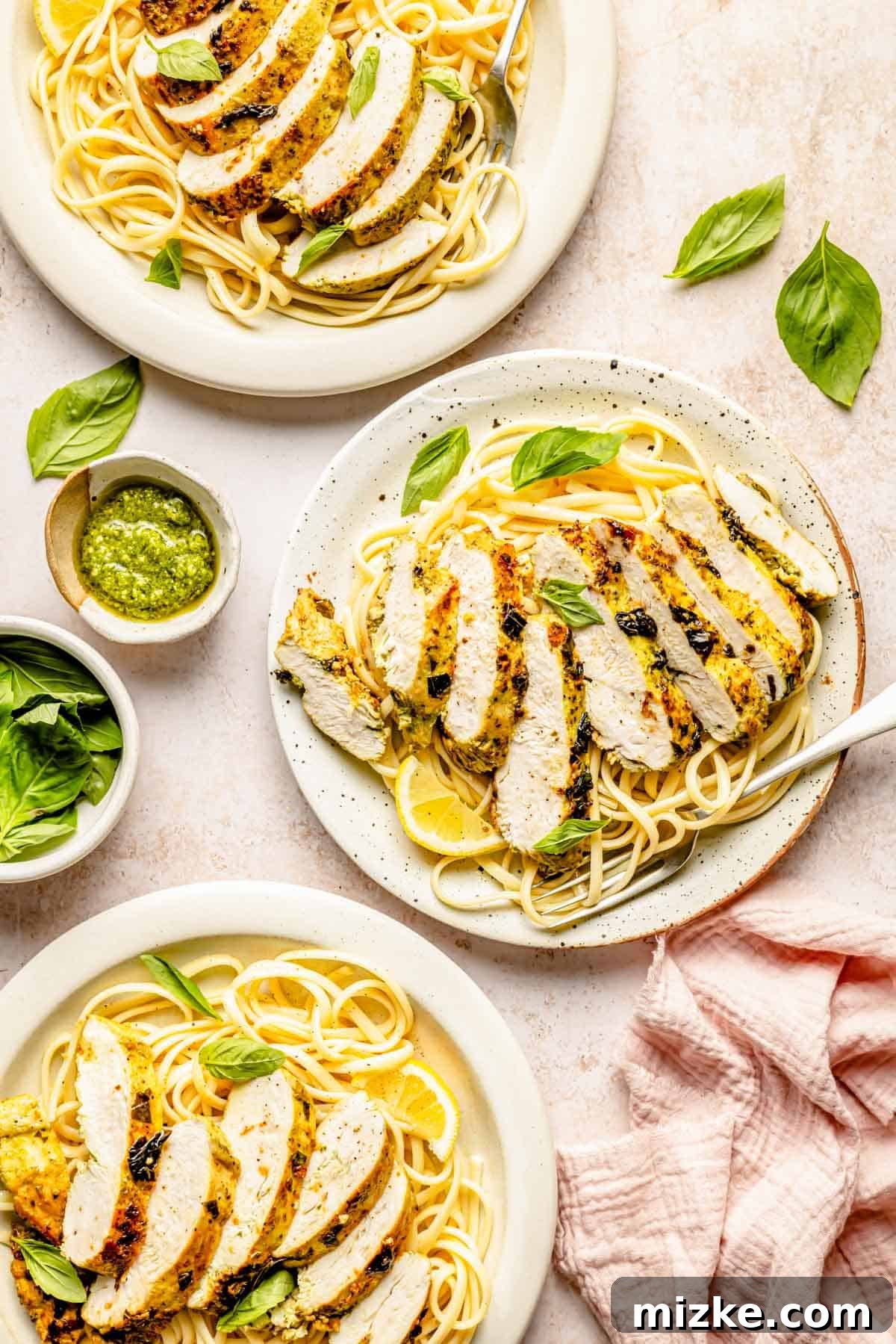 sliced lemon basil chicken plated on top of spaghetti noodles