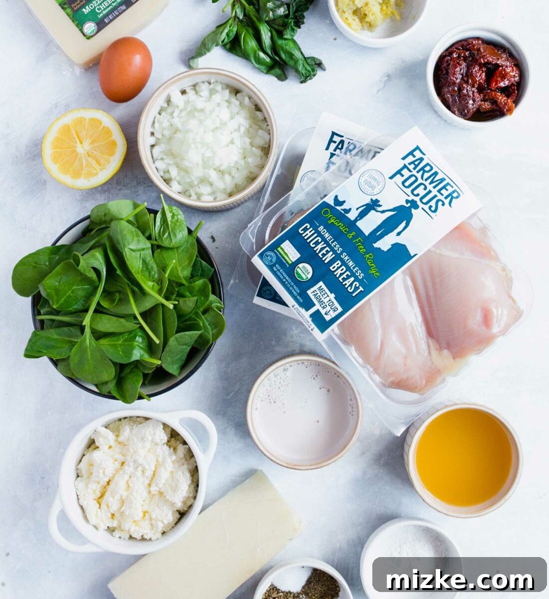 Sun-Kissed Tomato and Spinach Stuffed Chicken 3 All the fresh ingredients for the stuffed chicken breasts and creamy sauce laid out neatly on a white kitchen counter.