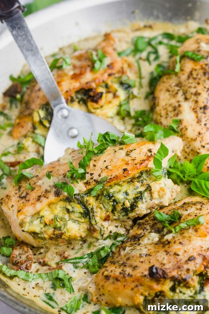 Sun-Kissed Tomato and Spinach Stuffed Chicken 5 A kitchen spatula carefully lifting a perfectly cooked stuffed chicken breast, garnished with fresh basil, from a hot skillet.