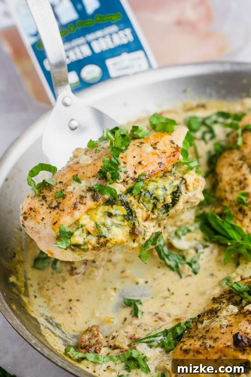 Sun-Kissed Tomato and Spinach Stuffed Chicken 6 A chef's hand delicately lifting a cooked, golden-brown stuffed chicken breast from the skillet, ready to be plated.