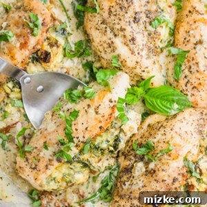 A beautifully presented stuffed chicken breast, sliced to reveal its creamy filling, served alongside pasta and topped with fresh basil.
