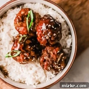 Four Mongolian meatballs on a bed of white rice in a bowl, placed on a wooden cutting board for a captivating food shot.
