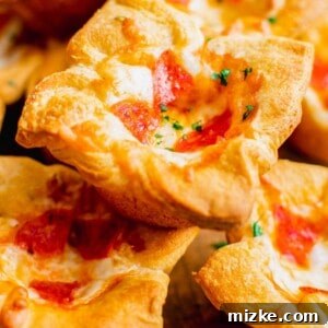 A perfectly baked pepperoni pizza muffin, garnished with fresh parsley, is stacked on top of several other golden-brown pizza muffins, showcasing their irresistible texture.