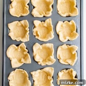 Portable Pizza Puffs 5 Crescent dough pressed into a 12-cup metal muffin tin, ready for filling.