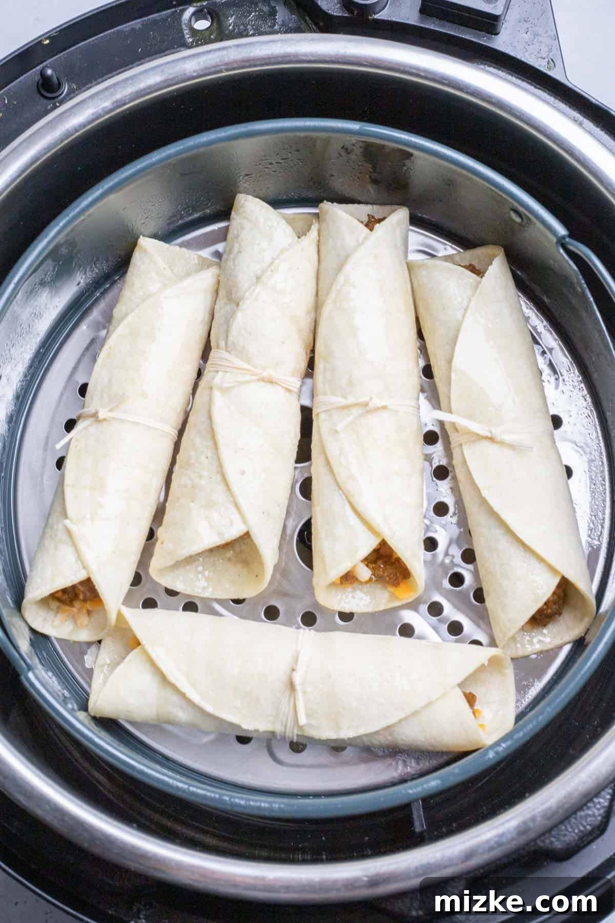 Crispy Air Fryer Beef Taquitos 9 Uncooked beef taquitos arranged neatly in the basket of an air fryer, ready for cooking.