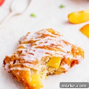 Golden Peach Bites 3 A peach fritter has been bitten into, revealing its fluffy interior and peach chunks.