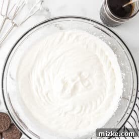 Oreo Cookie Bliss 13 Heavy whipping cream whipped to stiff peaks in a clear bowl, showing its airy texture.