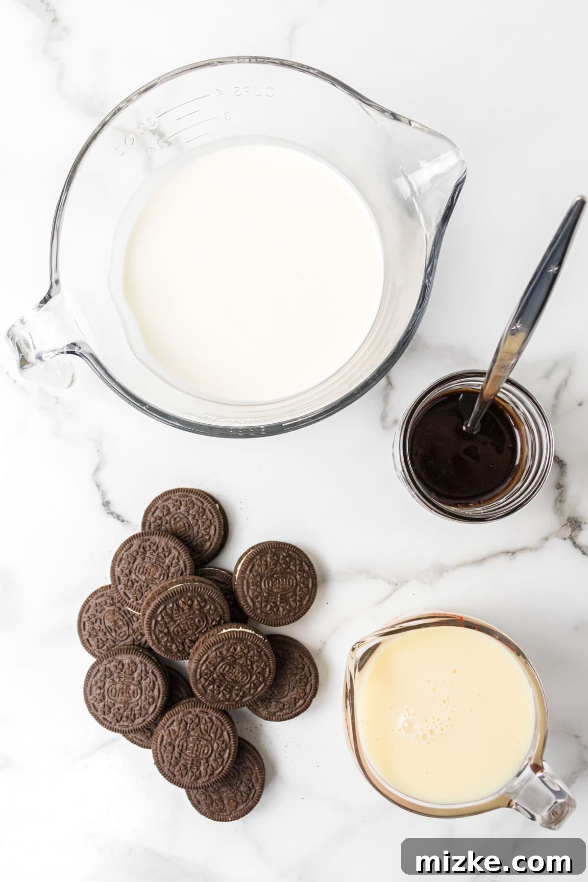 Oreo Cookie Bliss 3 A selection of fresh ingredients laid out for making Oreo ice cream: Oreos, heavy whipping cream, sweetened condensed milk, hot fudge topping, and vanilla extract.