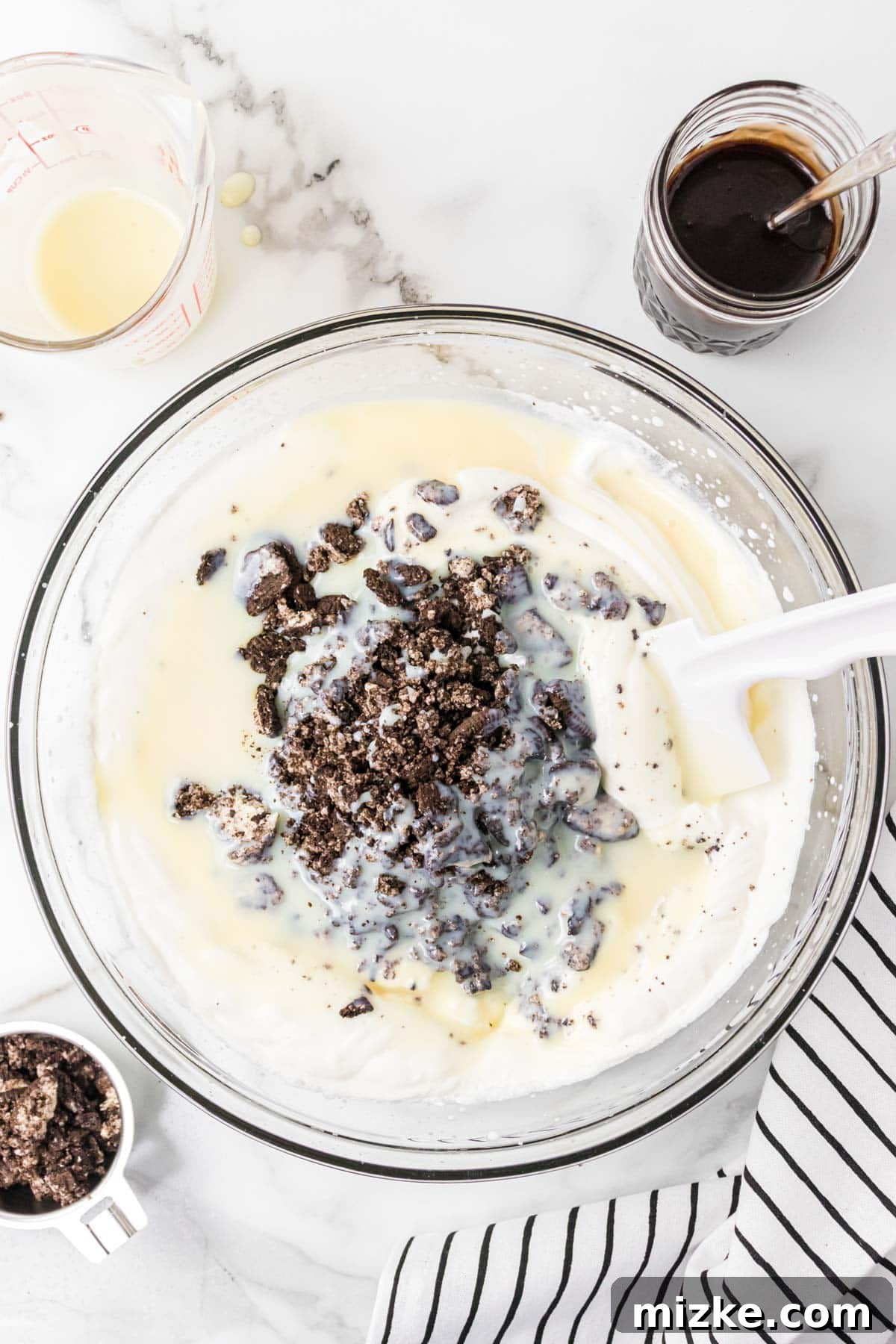 Oreo Cookie Bliss 8 Crushed Oreo cookies being folded into the creamy ice cream base in a mixing bowl.