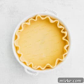 Savory Spinach and Artichoke Quiche 8 Raw pie dough in a pie dish with fork piercings for blind baking.