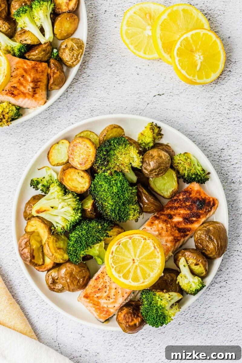 A white plate is filled with a salmon filet, potatoes and broccoli. 