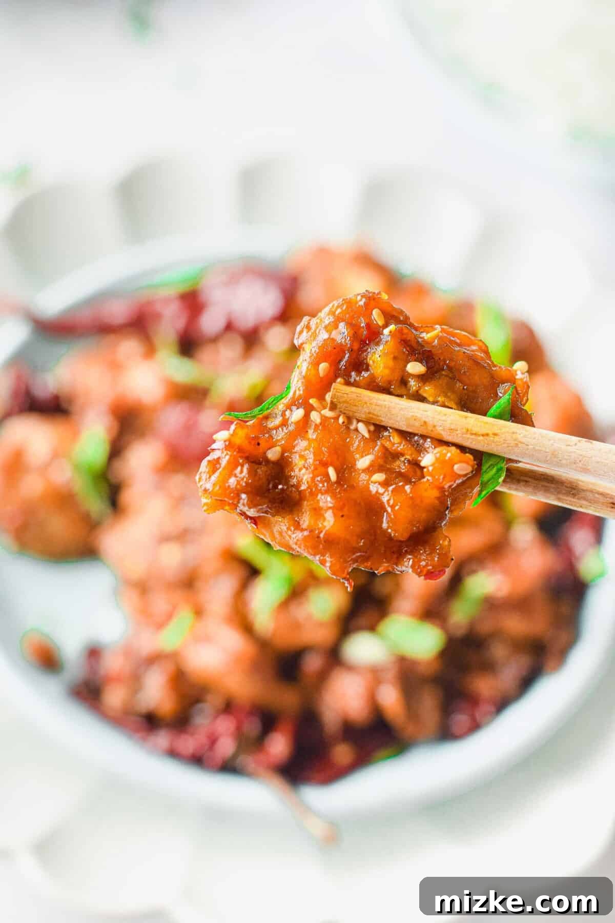 Speedy Restaurant-Style Instant Pot General Tso's Chicken 3 A piece of General Tso's Chicken being lifted with chopsticks, highlighting its crispy texture and glossy sauce.