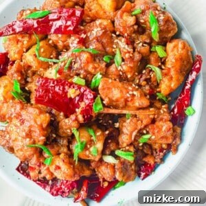 Cooked chicken is topped with peppers and green onions.