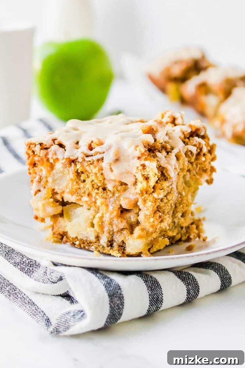 Cider Mill Coffee Cake 2 A beautifully presented slice of Apple Cider Coffee Cake on a white plate, showcasing its streusel topping and glaze.